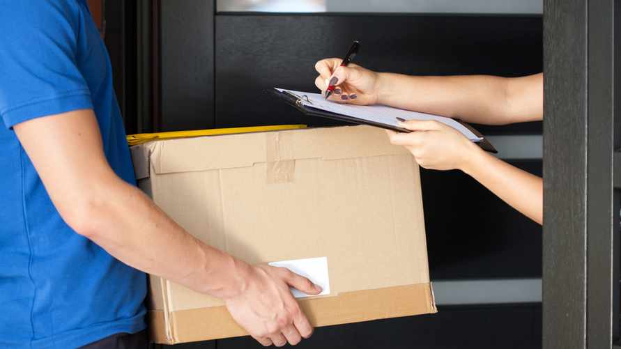 Delivery guy holding package while woman is signing documents