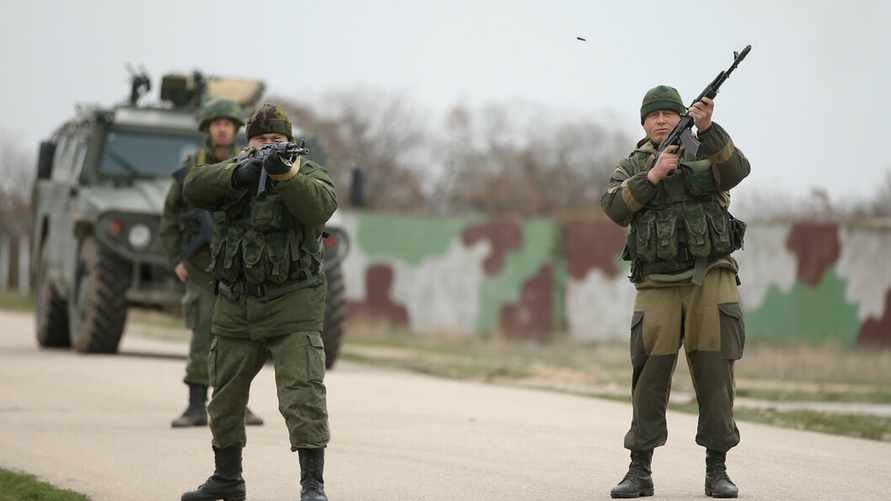 LUBIMOVKA, UKRAINE - MARCH 04: Troops under Russian command fire weapons into the air and scream orders to turn back at an approaching group of over 100 hundred unarmed Ukrainian troops at the Belbek airbase, which the Russian troops are occcupying, in Crimea on March 4, 2014 in Lubimovka, Ukraine. The Ukrainians are stationed at their garrison nearby, and after spending a tense night anticipating a Russian attack following the expiration of a Russian deadline to surrender, in which family members of troops spent the night at the garrison gate in support of the soldiers, their commander Colonel Yuli Mamchor announced his bold plan this morning to retake the airfield by confronting the Russian-lead soldiers unarmed. The Russian-lead troops fired their weapons into the air but then granted Mamchor the beginning of negotiations with their commander. Russian-lead troops have blockaded a number of Ukrainian military bases across Crimea. (Photo by Sean Gallup/Getty Images)