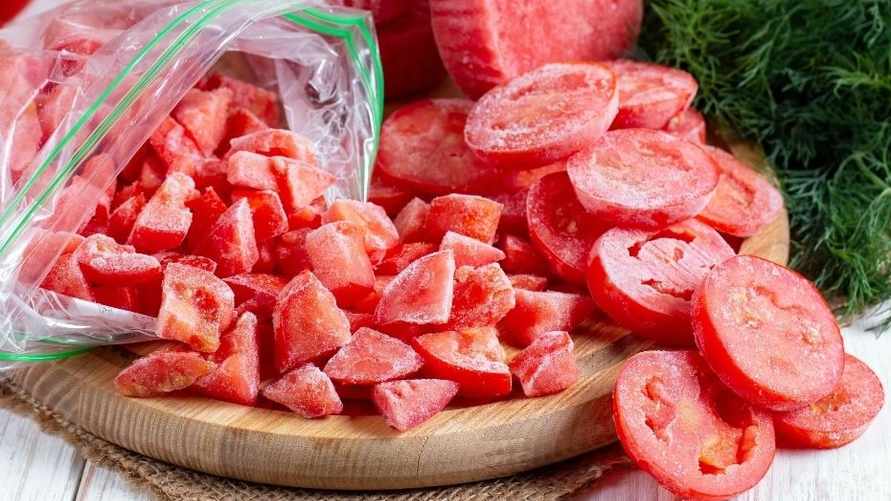 Frozen red tomatoes. Slices of frozen tomatoes on a wooden board