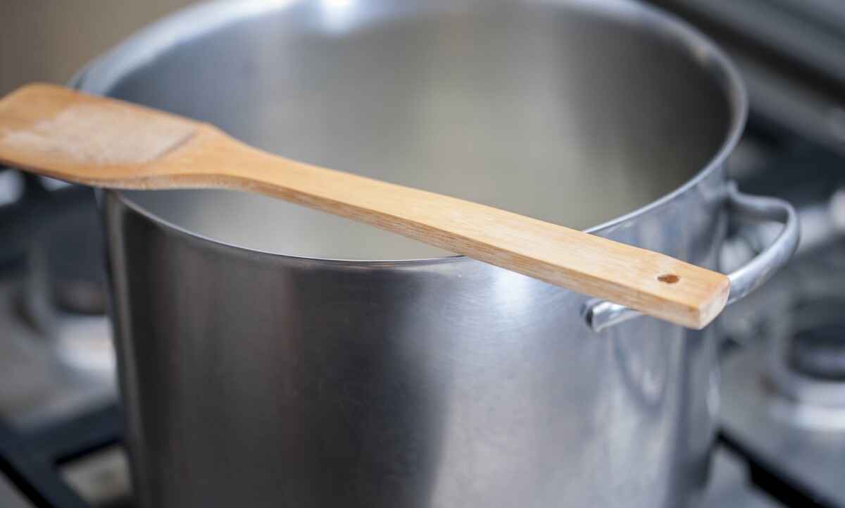 Wooden spoon over a hot metal pot while cooking a meal on a gas stove. Selecive focus. ; Shutterstock ID 411859555