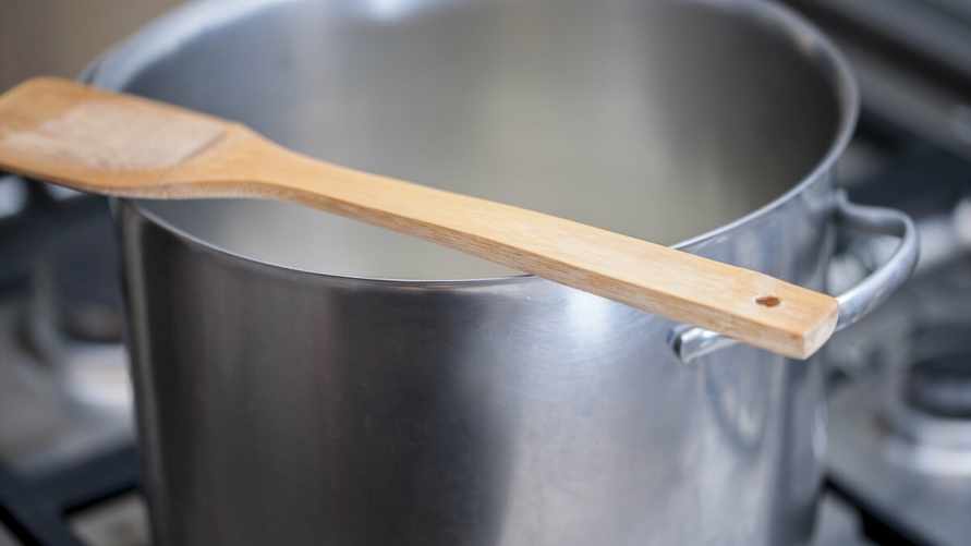 Wooden spoon over a hot metal pot while cooking a meal on a gas stove. Selecive focus. ; Shutterstock ID 411859555