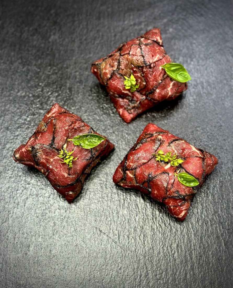 Говяжье корпаччо, посыпанное пудрой из жженой зелени